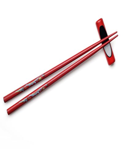 Red wooden chopsticks and chopstick rest on white background
