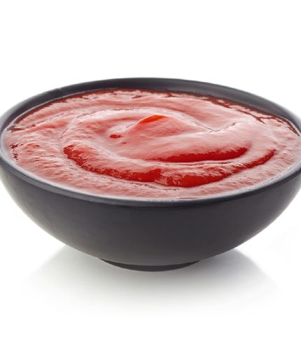 Black bowl of ketchup or tomato sauce on white background